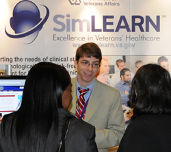 Attendees gather by SimLEARN wall banner